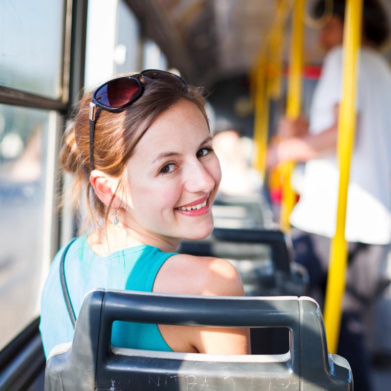 Uśmiechnięta kobieta jadąca autobusem.